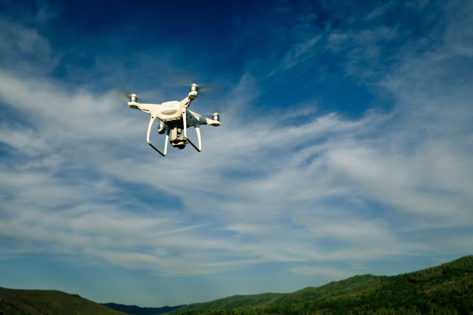 A white and yellow drone flying in the sky.