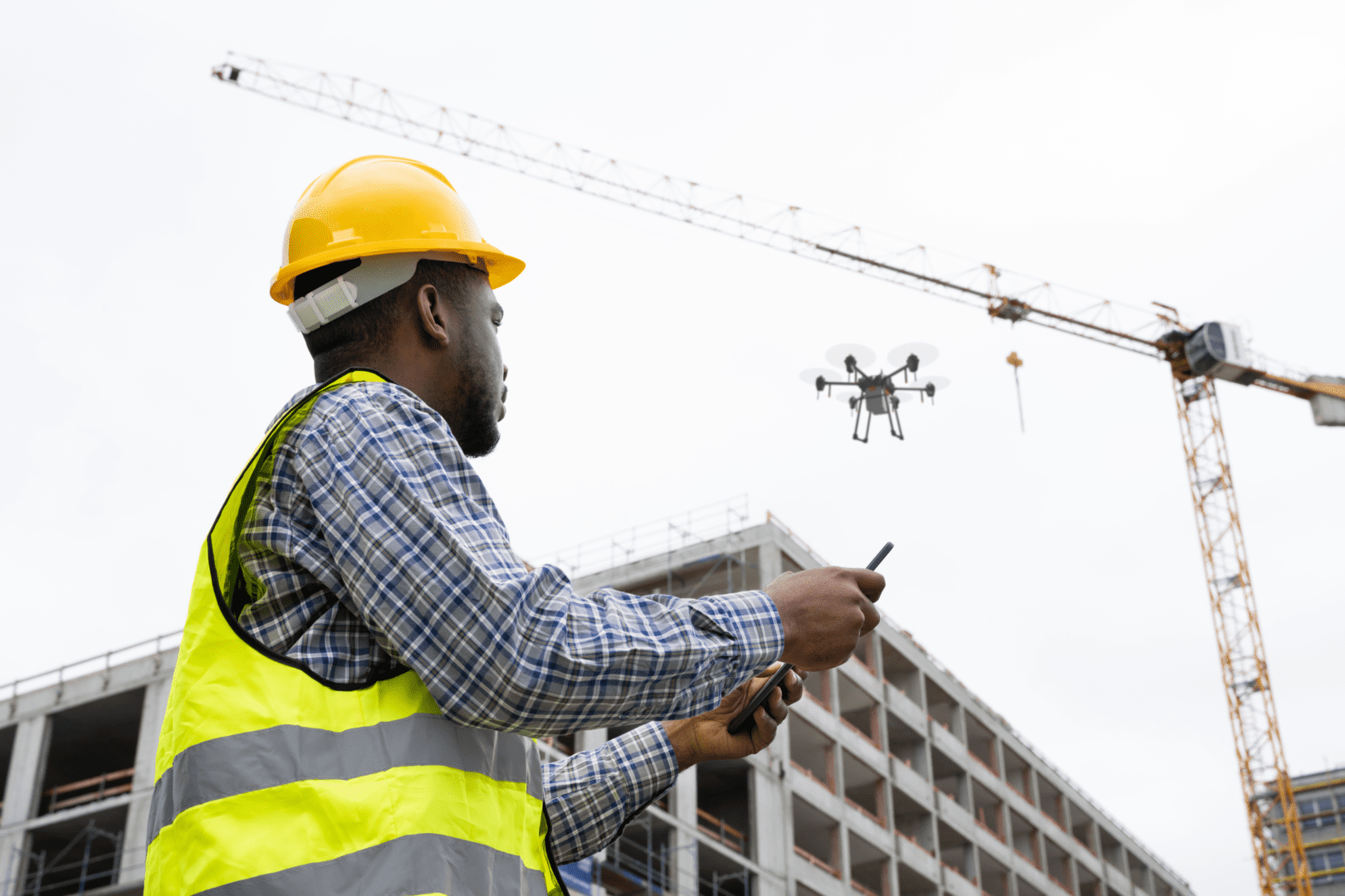 A man in yellow hard hat holding two cell phones.